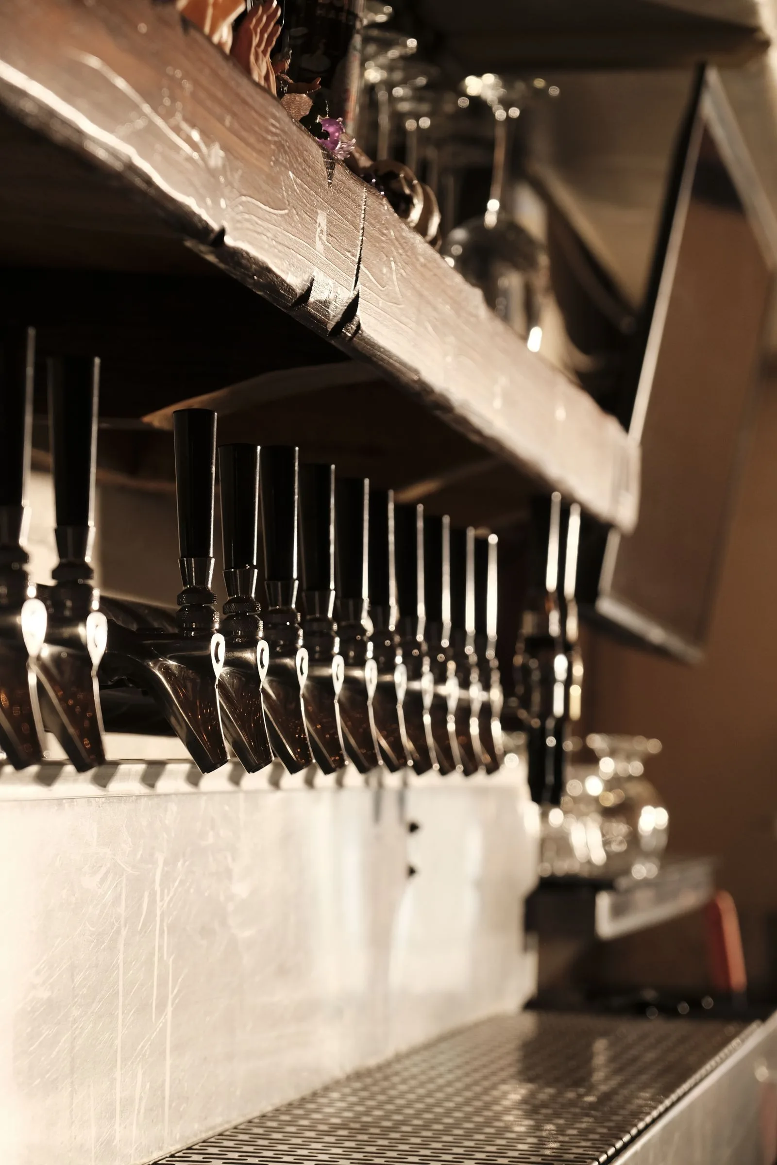 Lange rij bierkranen aan de muur van de taproom