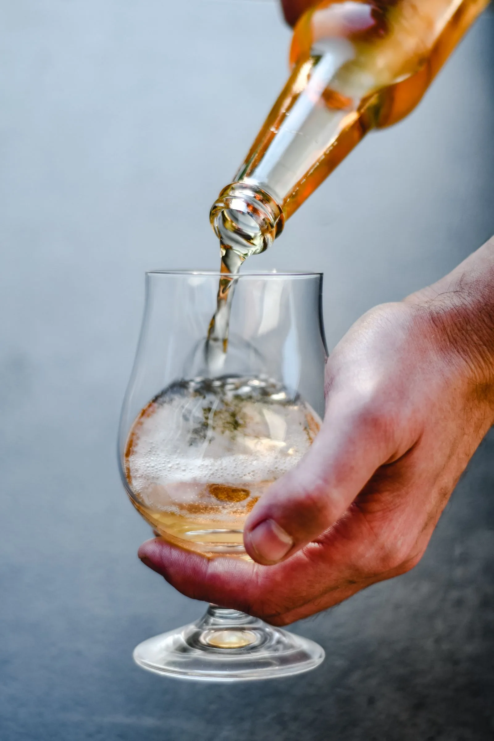Bier wordt uit een fles in een proefglas geschonken