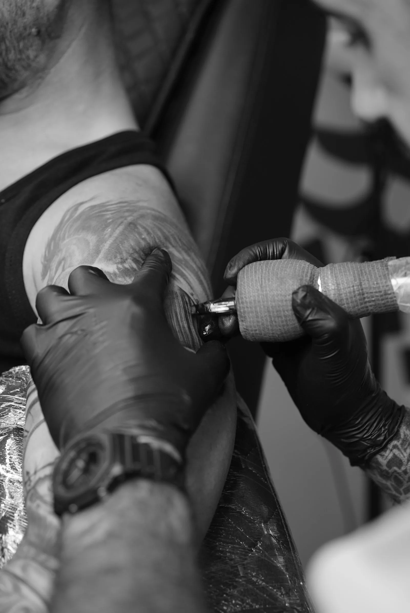 Tattoo-artiest met handschoenen aan het werk op een bovenarm