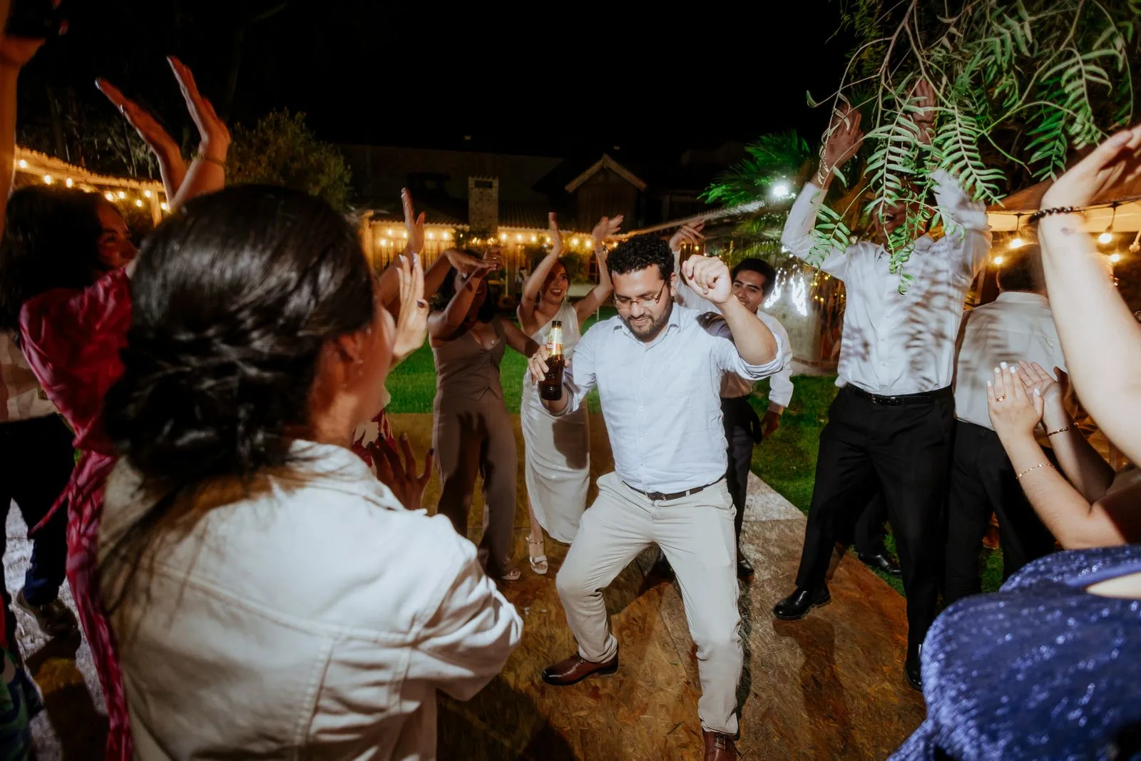 Gasten dansen buiten onder lichtsnoeren op een avondfeest