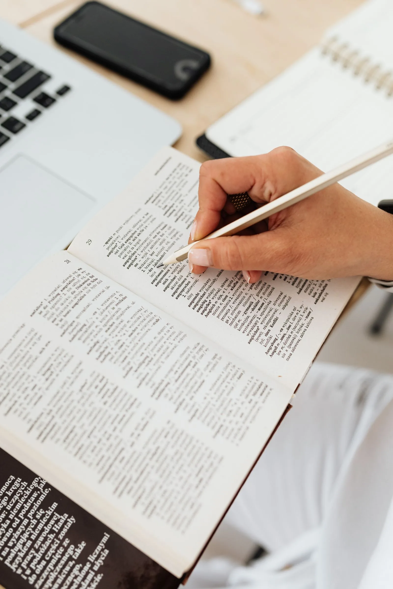 Iemand onderstreept woorden in een boek aan het bureau