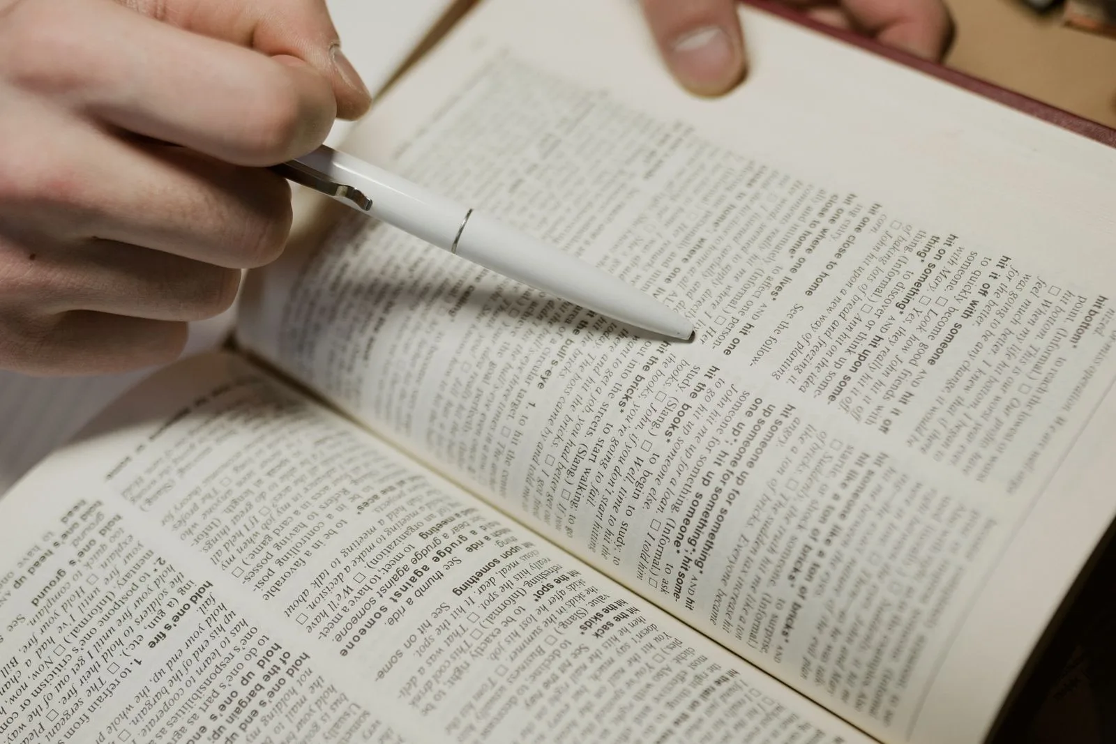 Een pen wijst een woord aan in een woordenboek