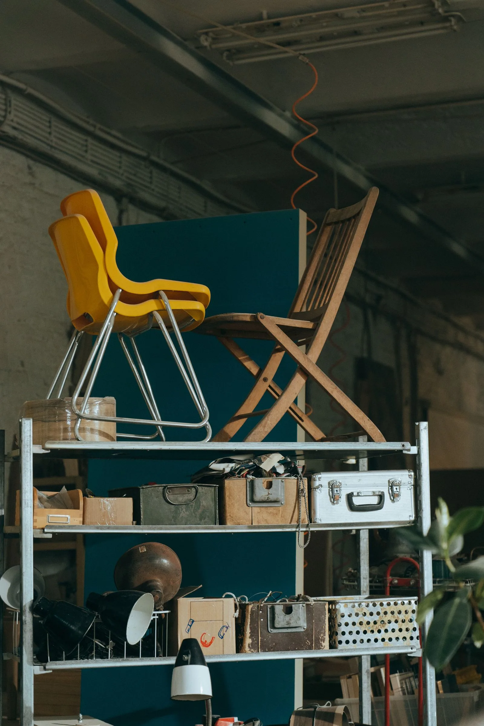 Rek met retro stoelen, koffers en lampen in een loods