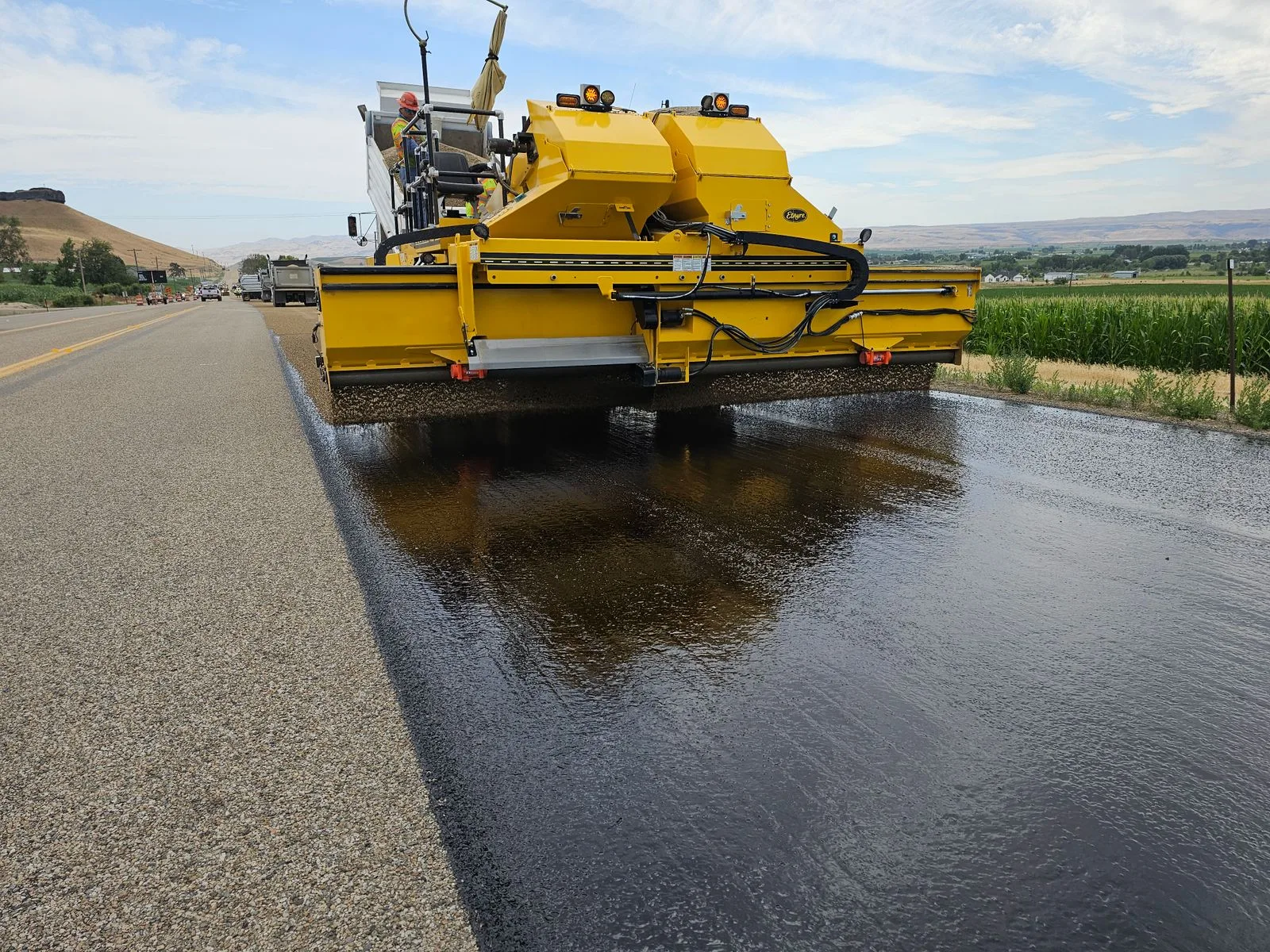 Een asfaltmachine legt een nieuwe toplaag op een landelijke weg
