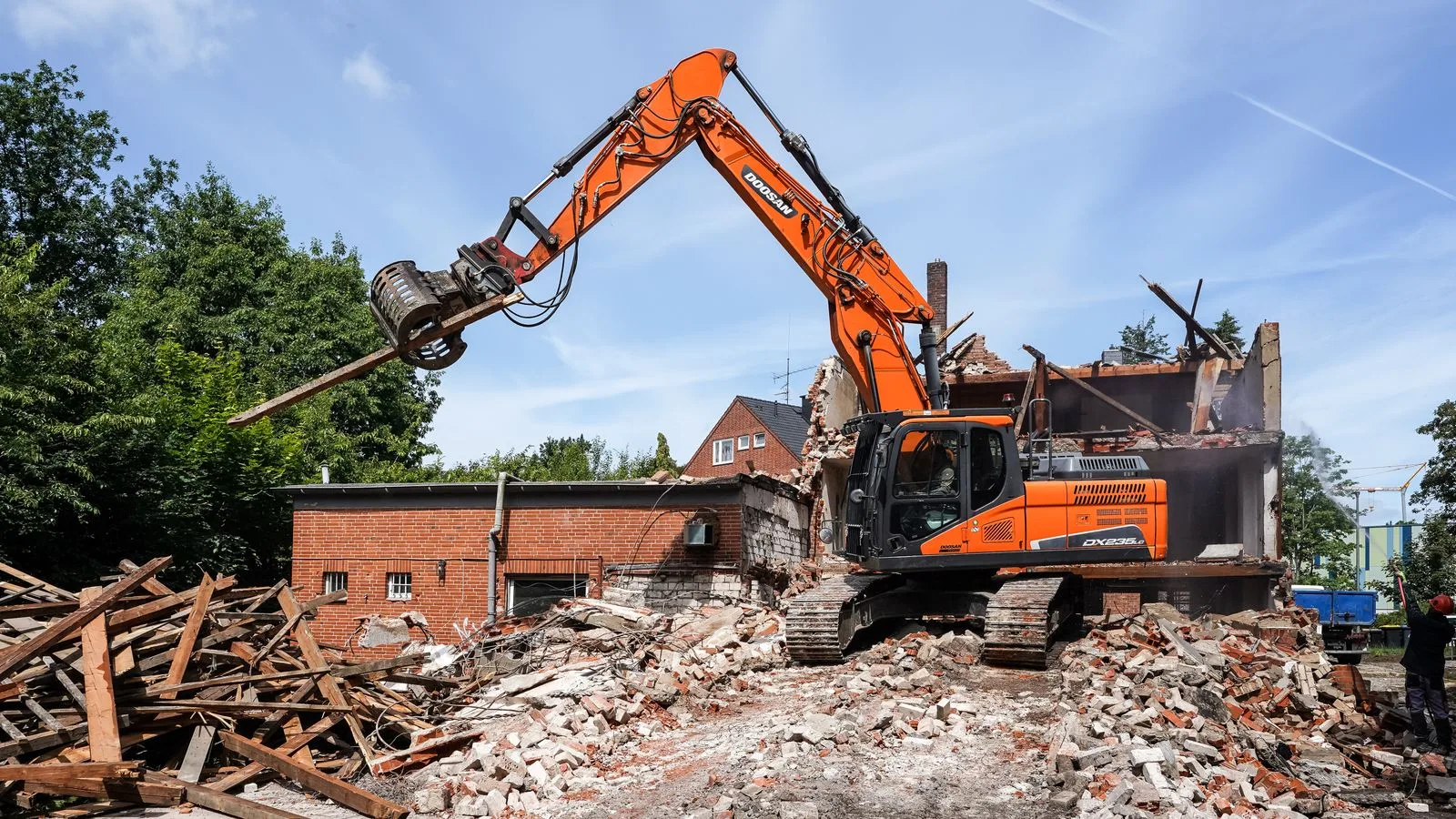 Een graafmachine sloopt een bakstenen gebouw
